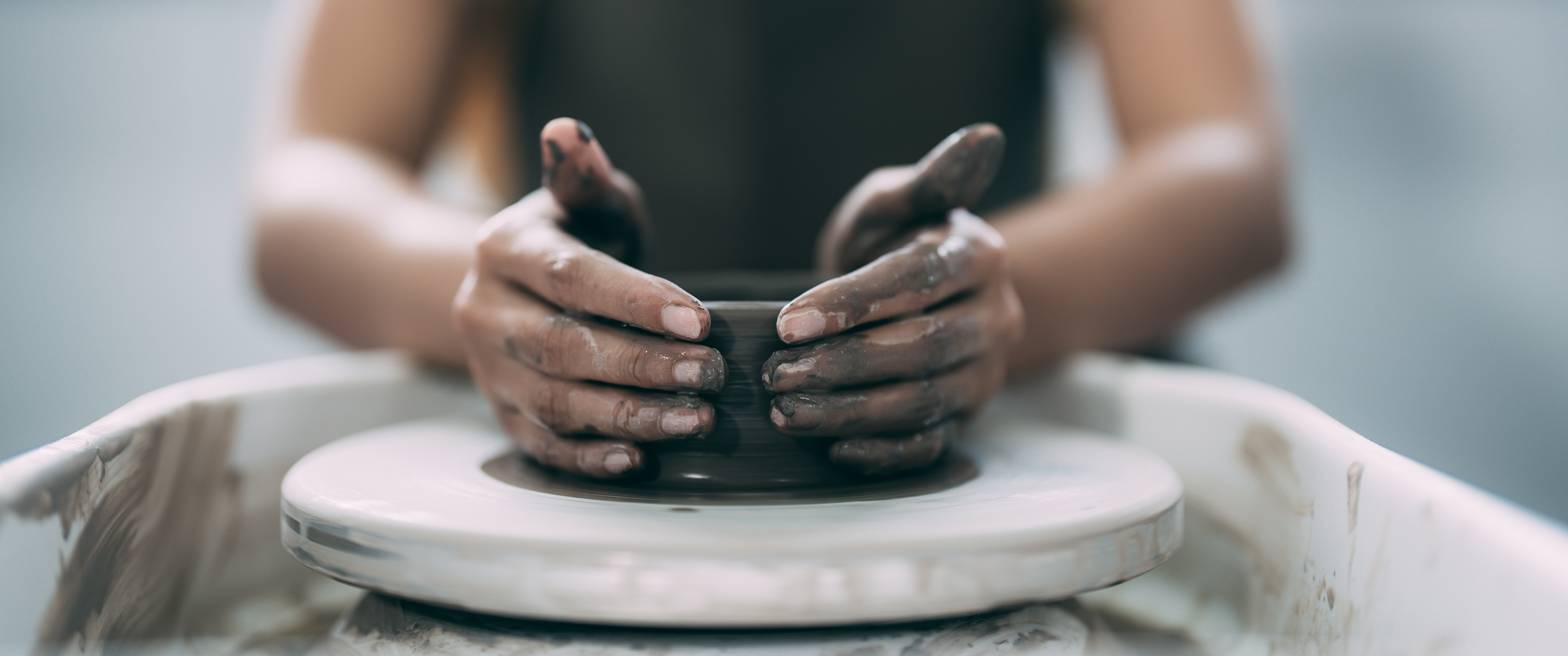 Hands shaping clay on a pottery wheel